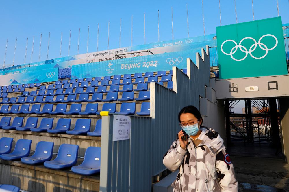 A woman walks past the spectator stand at the Big Air Shougang, a competition venue for freestyle skiing and snowboard at the Beijing 2022 Winter Olympics, during an organised media tour, in Beijing, China December 15, 2021. REUTERSpix