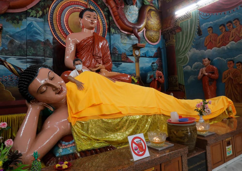 Volunteer Sunny Foong draping the statue of Buddha with yellow coloured cloth at the Buddha Mahindarama temple in Jalan Kampar for Wesak Day celebrations.- MASRY CHE ANI/THE SUN