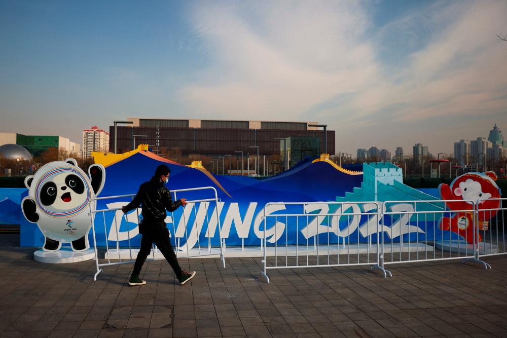 A woman has her picture taken in front of a Beijing 2022 installation near the closed loop “bubble” surrounding venues of the Beijing 2022 Winter Olympics in Beijing, China, January 18, 2022. REUTERSpix