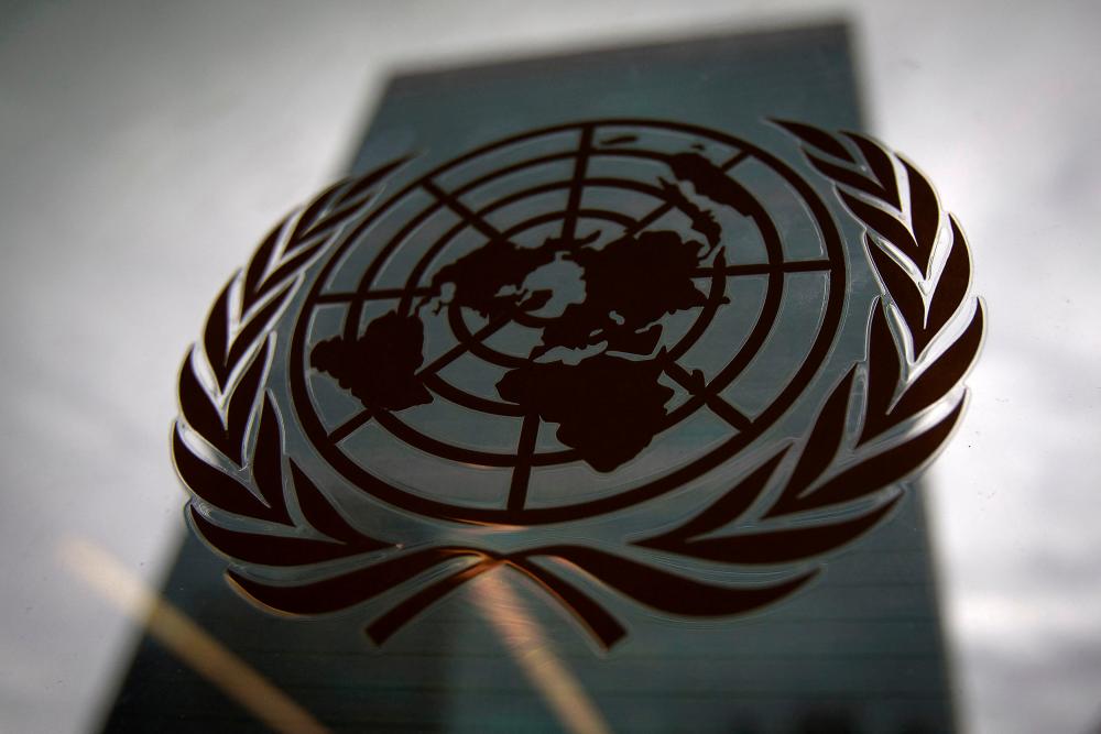 The United Nations headquarters building is pictured though a window with the UN logo in the foreground in the Manhattan borough of New York August 15, 2014. REUTERSPIX