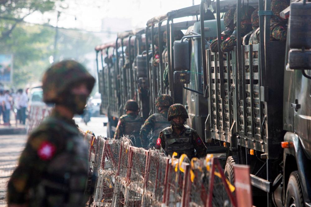 FILE PHOTO: Soldiers stand next to military vehicles as people gather to protest against the military coup, in Yangon, Myanmar, February 15, 2021. REUTERSPIX
