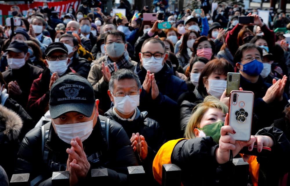 People wearing protective masks pray at the annual bean-scattering ceremony to celebrate the upcoming arrival of spring and wish to drive out the coronavirus disease (COVID-19) pandemic at the Naritasan Shinshoji temple in Narita, near Tokyo, Japan, February 3, 2022. REUTERSpix