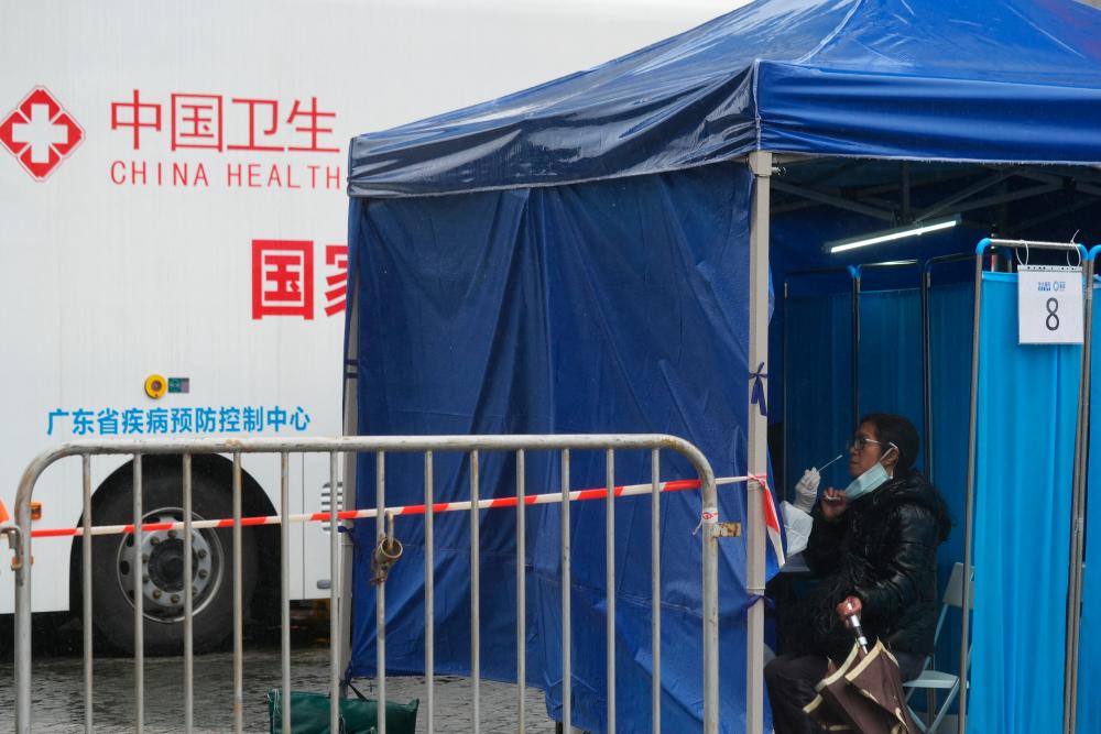A medical worker collects a swab sample from a person at a makeshift testing site next to a mobile testing vehicle with a sign of Guangdong Provincial Center for Disease Prevention and Control, following the coronavirus disease (COVID-19) outbreak, in Tung Chung, Hong Kong, China February 21, 2022. REUTERSPIX