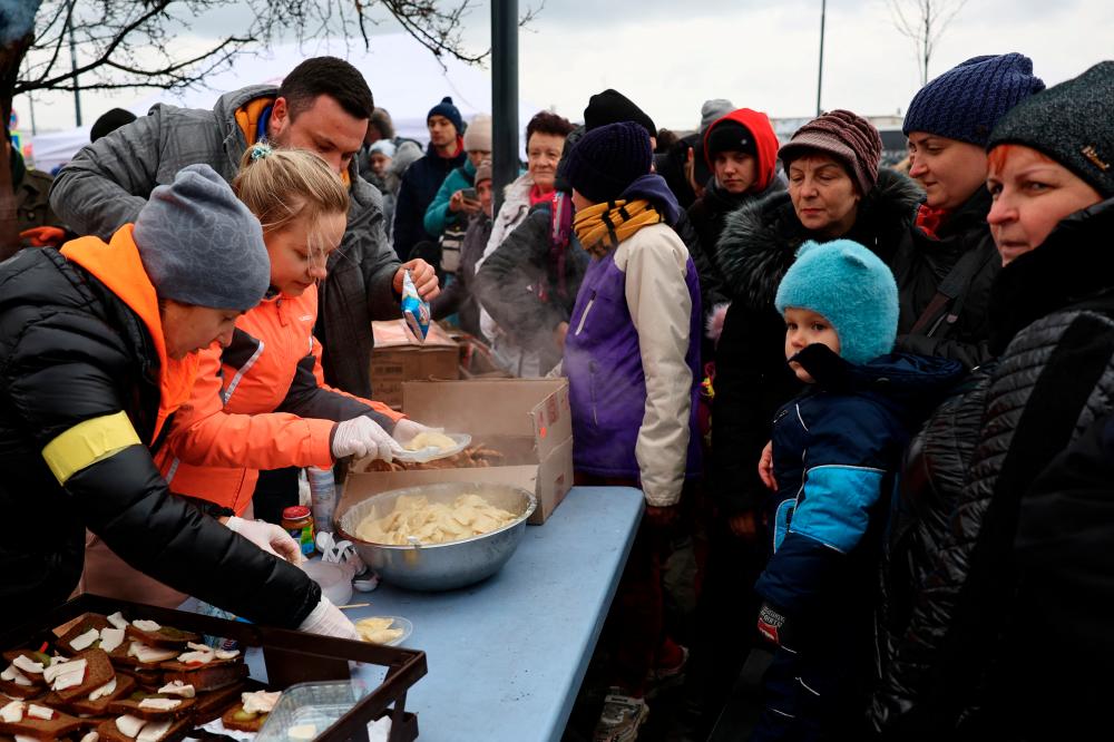 Refugees share a meal as they wait for transfer after fleeing the ongoing Russian invasion at the main train station in Lviv, Ukraine, March 5, 2022. - REUTERSpix