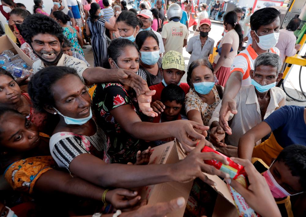 People are given packets of biscuits from a free distributor, while waiting in line to buy kerosene near a Ceylon Petroleum Corporation fuel station, amid the country’s economic crisis in Colombo, Sri Lanka/REUTERSPix