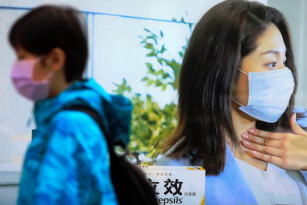 A pedestrian walks past a medicine advertisement with a woman wearing a face mask, in Taipei, Taiwan. - REUTERSPIX