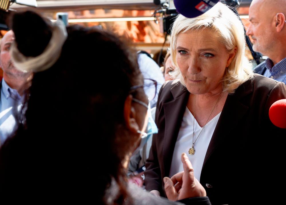 A person speaks to Marine Le Pen, French far-right National Rally (Rassemblement National) party candidate in the 2022 French presidential election, during her visit to a market as she campaigns in Pertuis, near Marseille in the south of France, April 15, 2022. REUTERSPIX