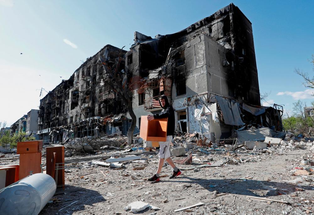 A local resident takes furniture out of an apartment building heavily damaged during Ukraine-Russia conflict in the southern port city of Mariupol/REUTERSPix