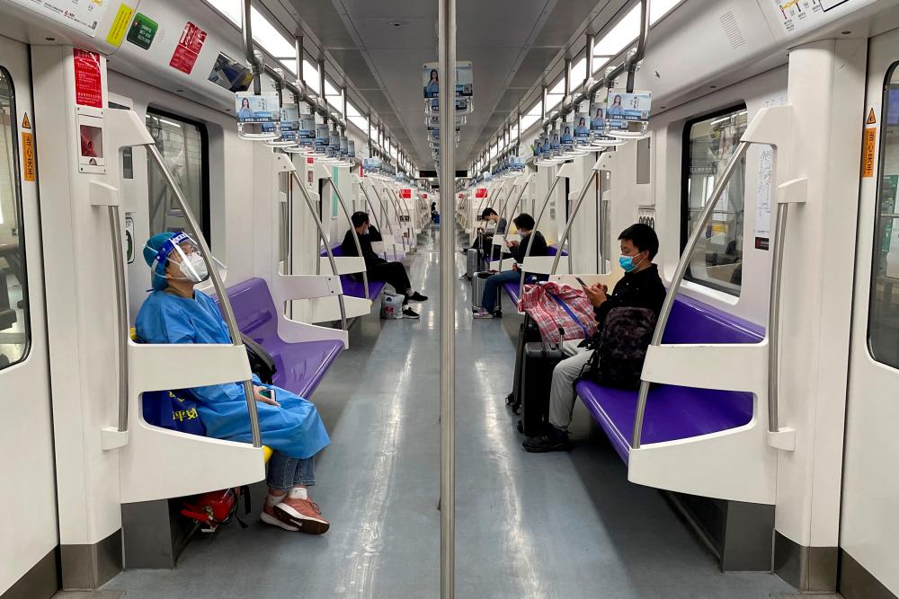 A passenger in a protective suit rides on a subway train on the first day of parts of city’s subway services resumed, following the coronavirus disease (COVID-19) outbreak, in Shanghai, China May 22, 2022. REUTERSPIX