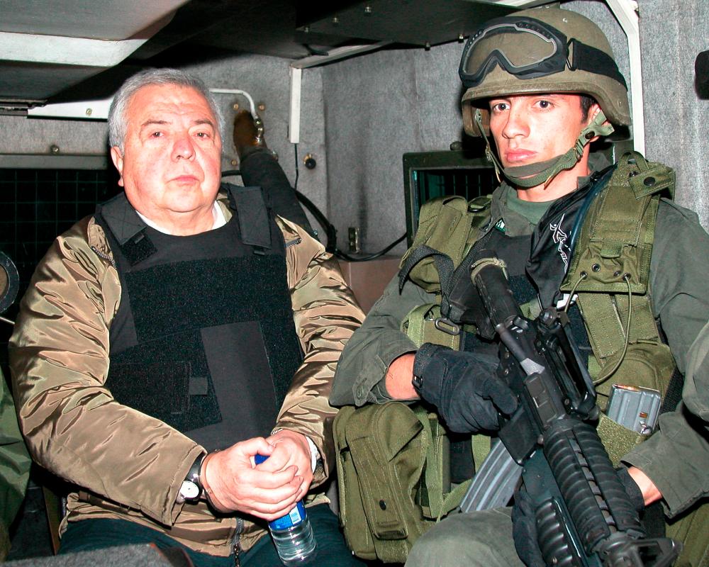 The former boss of the powerful Cali cartel, Gilberto Rodriguez Orejuela is escorted by a Colombian policeman before being extradited to the United States on December 3, 2004. - REUTERSPIX
