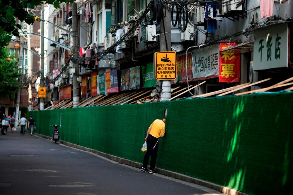 A man looks in through a gap in a barrier in a residential area, after the lockdown placed to curb the coronavirus disease (COVID-19) outbreak was lifted in Shanghai, China June 7, 2022. REUTERSPIX