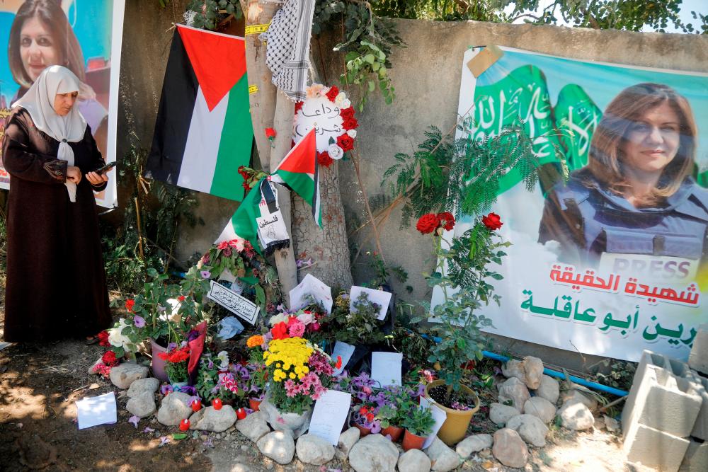 FILE PHOTO: A Palestinian woman takes pictures at the scene where Al Jazeera reporter Shireen Abu Akleh was shot dead during an Israeli raid, in Jenin, in the Israeli-occupied West Bank, May 17, 2022. Picture taken May 17, 2022. REUTERSPIX