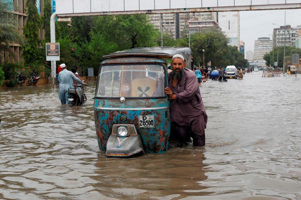 A man pushes his rickshaw (tuk tuk) through a flooded road during the monsoon season in Karachi, Pakistan July 9, 2022. REUTERSPIX