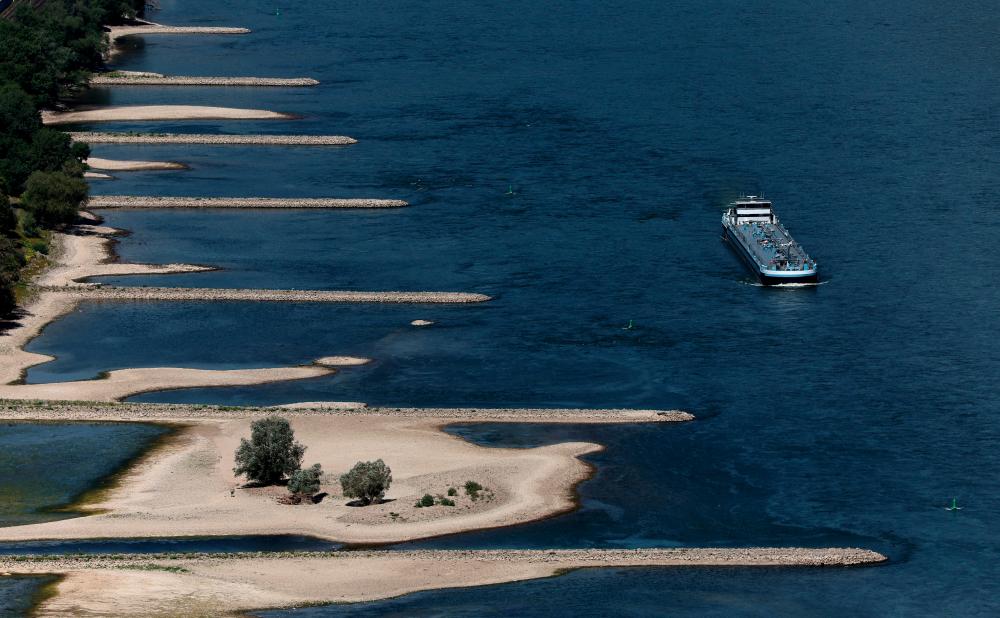 A transport vessel cruises past the partially dried riverbed of the Rhine river in Bingen, Germany/REUTERSPix