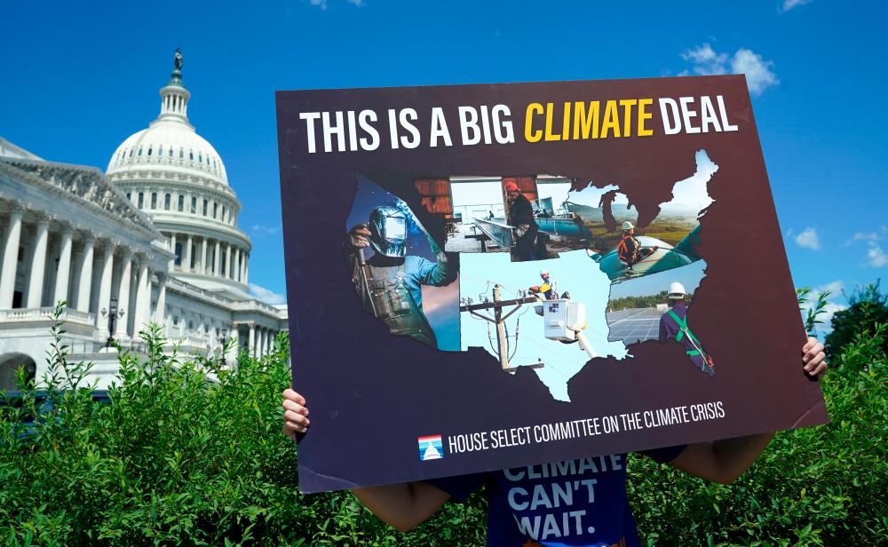 A volunteer holds a placard during a news conference on the climate crisis and the Inflation Reduction Act at the US Capitol in Washington, DC, US, August 12, 2022. REUTERSPIX