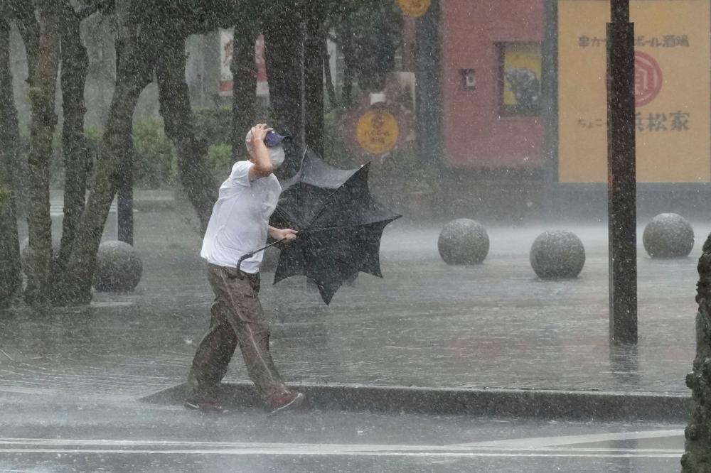 A man walks on the street in the heavy rain caused by Tropical Storm Meari in Hamamatsu, central Japan August 13, 2022, in this photo taken by Kyodo. - REUTERSPIX