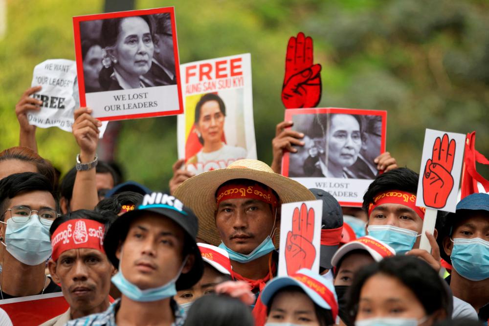 FILE PHOTO: Demonstrators hold placards with pictures of Aung San Suu Kyi as they protest against the military coup in Yangon, Myanmar, February 22, 2021. REUTERSpix