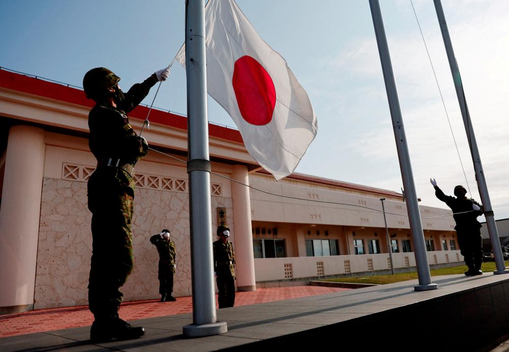 FILE PHOTO: Members of the Japan Ground Self-Defense Force (JGSDF) bring down the Japanese national flag in the early evening, at JGSDF Miyako camp on Miyako Island, Okinawa prefecture, Japan April 20, 2022. - REUTERSPIX