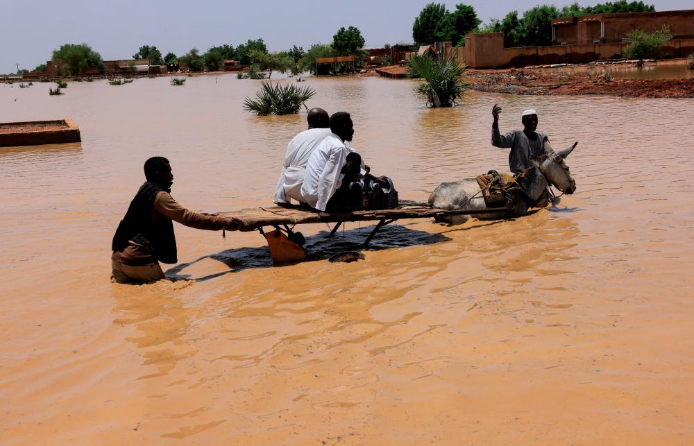 People ride a donkey cart to cross the water during flood in Al-Managil locality in Jazeera State, Sudan, August 23, 2022. - REUTERSPIX