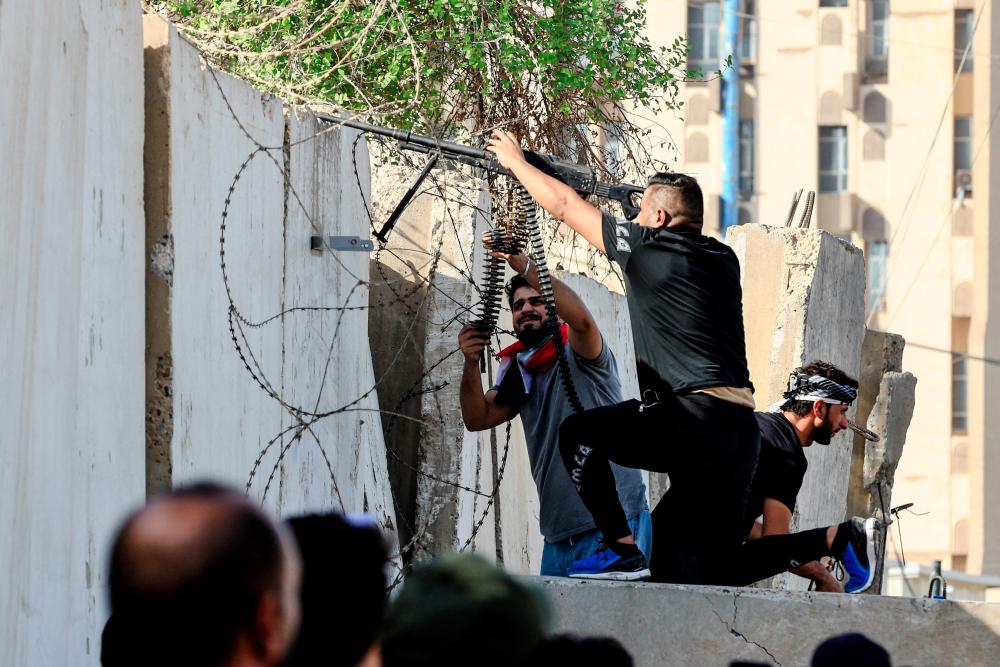 Sadr's Peace Brigades fighters fire their weapons during clashes with the Iraqi security forces near the Green Zone, in Baghdad, Iraq August 30, 2022. - REUTERSPIX