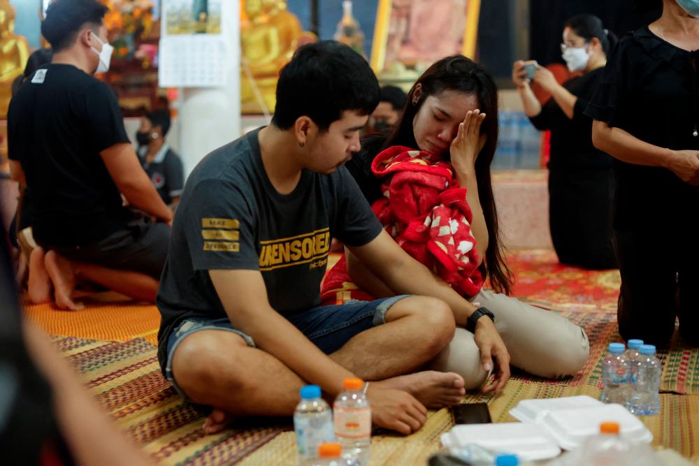 Relatives react at Wat Rat Samakee temple, near the coffins of victims, following a mass shooting in the town of Uthai Sawan, Nong Bua Lam Phu province, Thailand October 7, 2022. - REUTERSPIX
