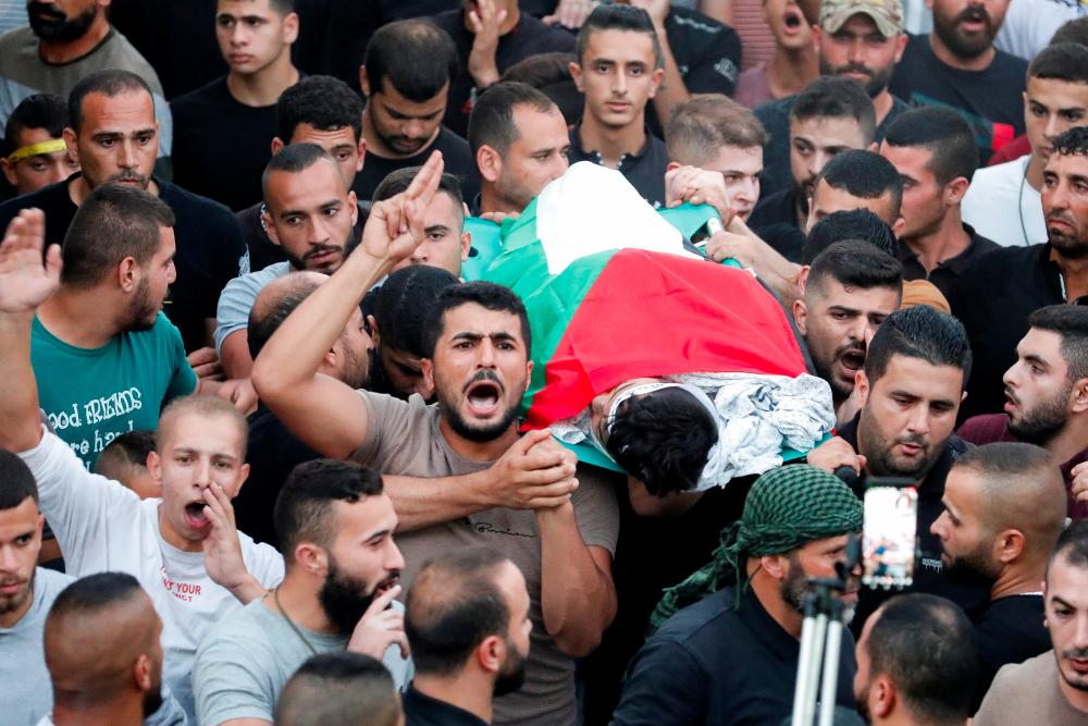 SENSITIVE MATERIAL. THIS IMAGE MAY OFFEND OR DISTURB People carry the body of Mahmoud Samoudi, 12, who died of a wound he sustained during an Israeli raid in Jenin, during his funeral, in the Israeli-occupied West Bank, October 10, 2022. - REUTERSPIX