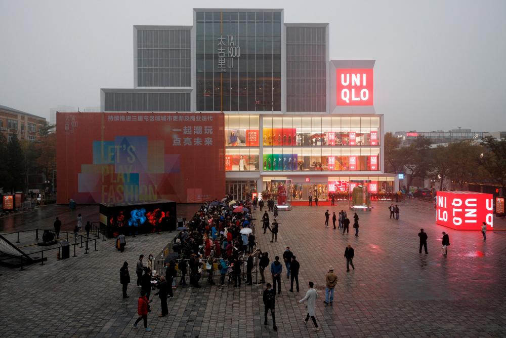 FILE PHOTO: Customers line up outside store of the Uniqlo fast fashion retailer to attend its opening in the Sanlitun shopping district on a polluted day in Beijing, China, November 6, 2021. REUTERSPIX