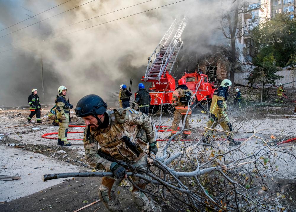 Firefighters help a local woman evacuate from a residential building destroyed by a Russian drone strike, which local authorities consider to be Iranian-made unmanned aerial vehicles (UAVs) Shahed-136, amid Russia’s attack on Ukraine, in Kyiv, Ukraine/REUTERSPix