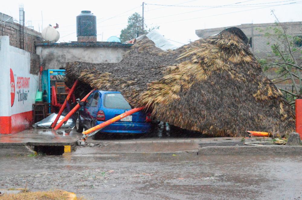 A fallen palm leaf shades, known as palapa, lies on a crushed car following the passing of Hurricane Roslyn that hit the Mexico’s Pacific coast with heavy winds and rain, in Tecuala in Nayarit state, Mexico. October 23, 2022. REUTERSPIX