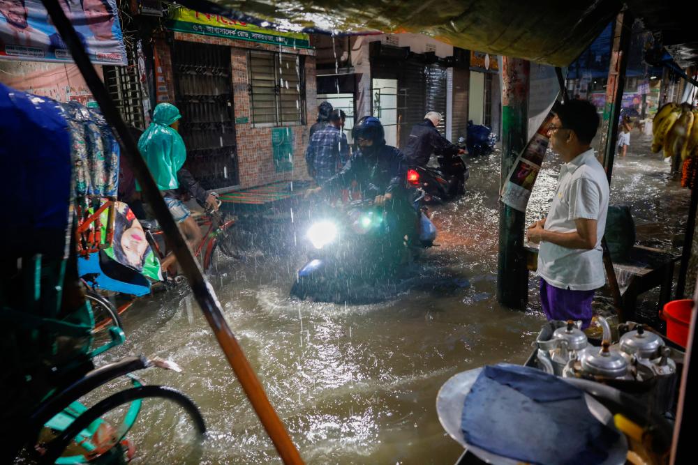 People ride rickshaws and motorcycle on a flooded street, amid continuous rain before the Cyclone Sitrang hits the country in Dhaka, Bangladesh, October 24, 2022. REUTERSPIX