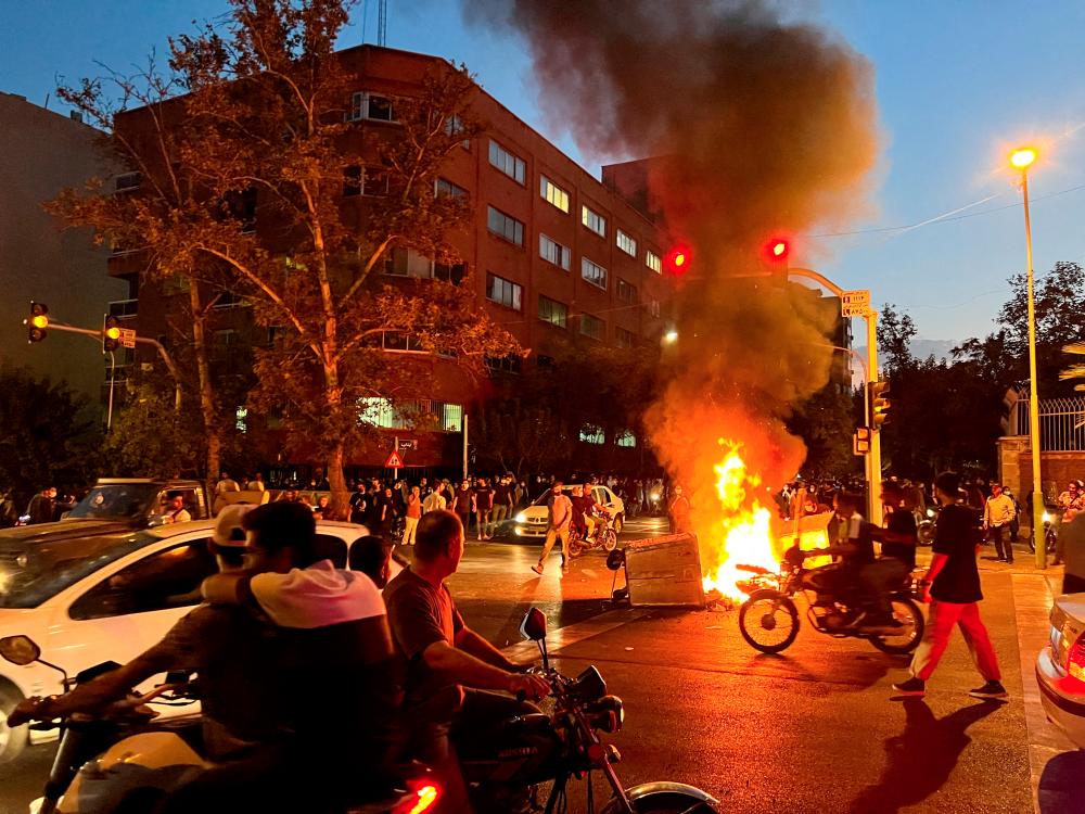 FILE PHOTO: A police motorcycle burns during a protest over the death of Mahsa Amini, a woman who died after being arrested by the Islamic republic's morality police, in Tehran, Iran September 19, 2022. - REUTERSPIX