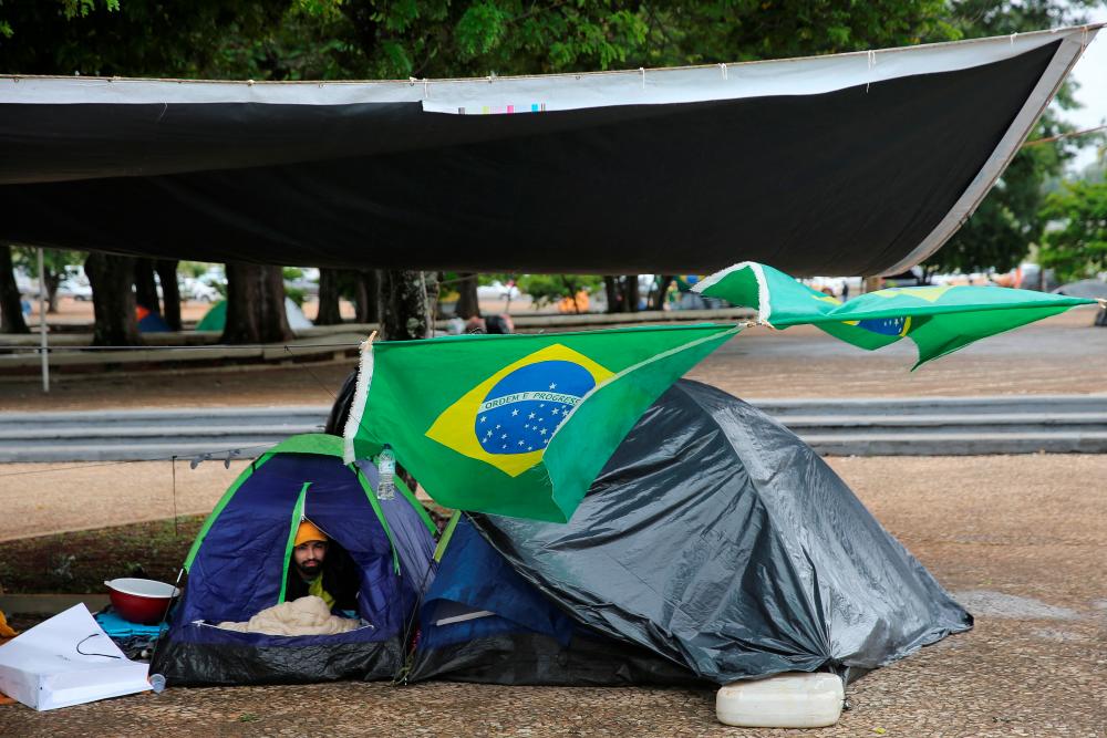 A person looks out from a tent during a protest held by supporters of Brazil’s President Jair Bolsonaro against President-elect Luiz Inacio Lula da Silva who won a third term following the presidential election run-off, at the Army Headquarters in Brasilia, Brazil, November 3, 2022. REUTERSPIX