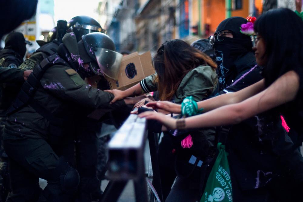 Demonstrators and riot police members push from opposite sides of a barrier during a protest to mark the International Day for the Elimination of Violence Against Women, in La Paz, Bolivia November 25, 2022/REUTERSPix