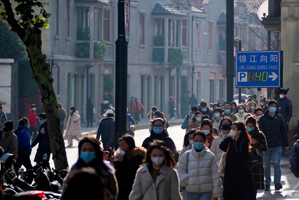 FILE PHOTO: People wearing face masks walk on a street, as coronavirus disease (COVID-19) outbreaks continue in Shanghai, China, December 13, 2022. - REUTERSPIX