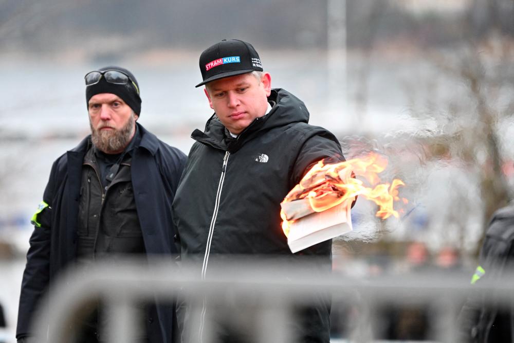 Leader of the far-right Danish political party Stram Kurs Rasmus Paludan burns a copy of the Koran during a manifestation outside the Turkish embassy in Stockholm, Sweden, January 21, 2023.- REUTERSPIX