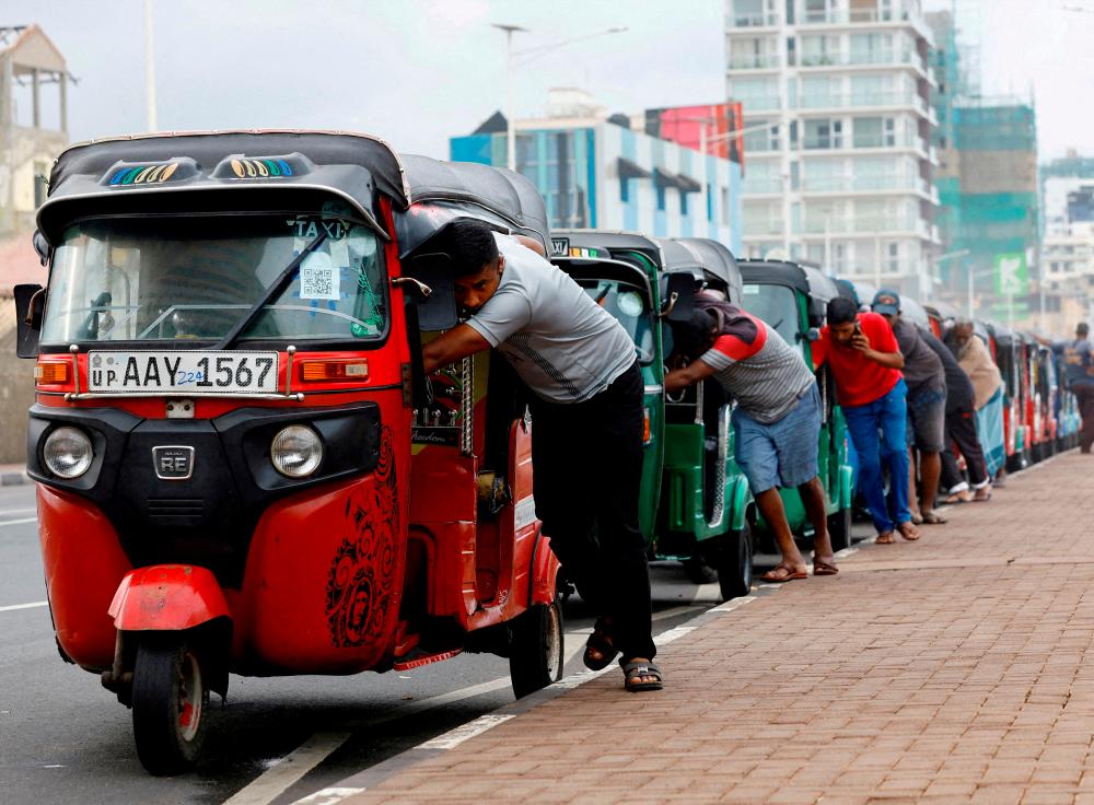 Drivers push auto rickshaws in a line to buy petrol from a fuel station amid Sri Lanka’s economic crisis, in Colombo, Sri Lanka, July 29, 2022. REUTERSpix