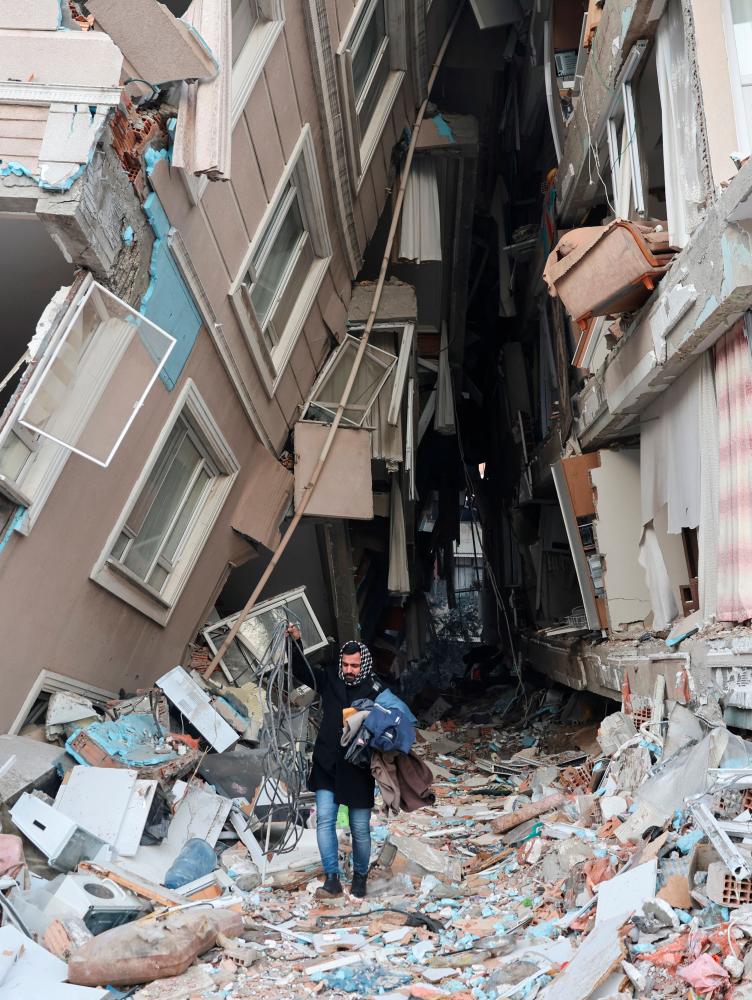 A survivor walks carrying belongings salvaged from his destroyed home, in the aftermath of a deadly earthquake in Hatay, Turkey February 9, 2023/REUTERSPix