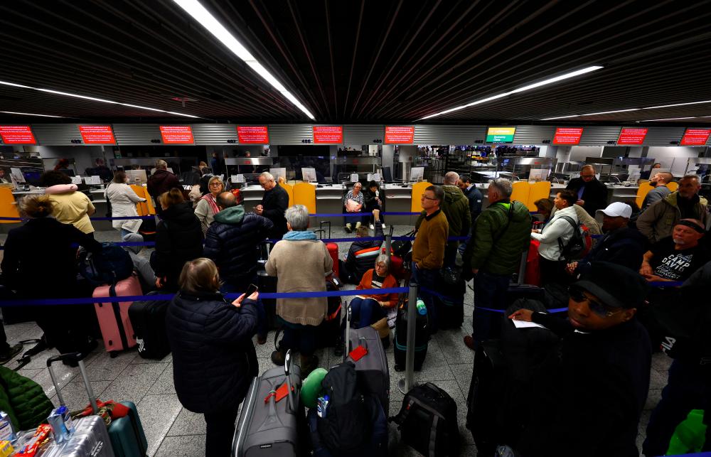 Passengers wait at a Lufthansa check in counter after an IT fault at Germany’s Lufthansa causes massive flight delays and disruptions in Frankfurt, Germany, February 15, 2023/REUTERSPix