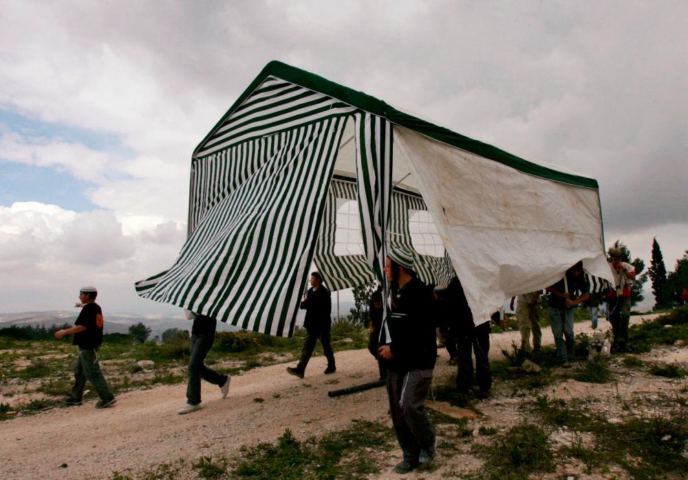 Israeli activists carry a tent in the abandoned Jewish settlement of Homesh, in the northern West Bank, March 27, 2007. REUTERSPIX