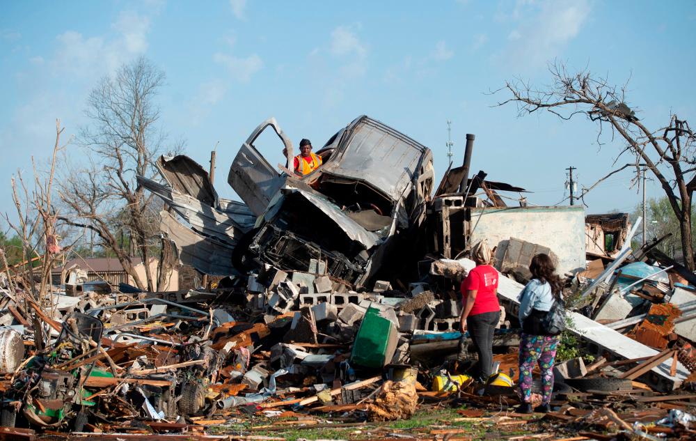 KeUntey Ousley tries to salvage what he can from his mother’s boyfriend’s vehicle, as his mother LaShata Ousley and his girlfriend Mikita Davis watch, after a tornado cut through their small Delta town the night before in Rolling Fork, Mississippi, U.S. March 25, 2023. REUTERSPIX