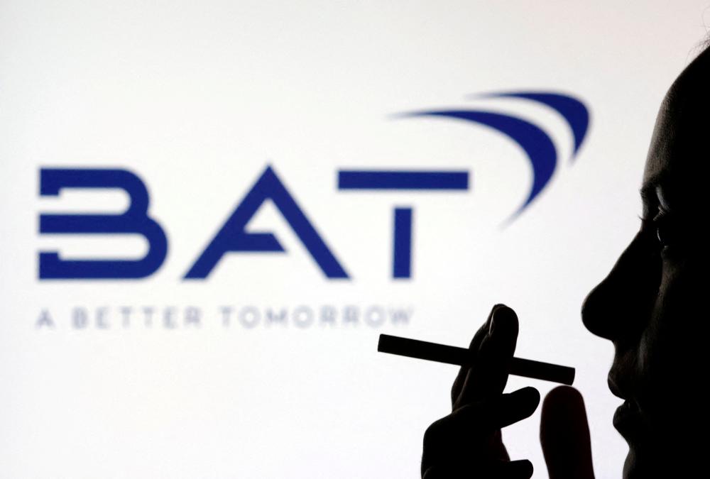 FILE PHOTO: A woman poses with a cigarette in front of BAT (British American Tobacco) logo in this illustration taken July 26, 2022. REUTERSPIX