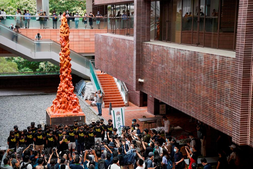 FILE PHOTO: University students observe a minute of silence in front of the “Pillar of Shame” statue at the University of Hong Kong on the 32nd anniversary of the crackdown on pro-democracy demonstrators at Beijing's Tiananmen Square in 1989, in Hong Kong, China June 4, 2021. REUTERSPIX