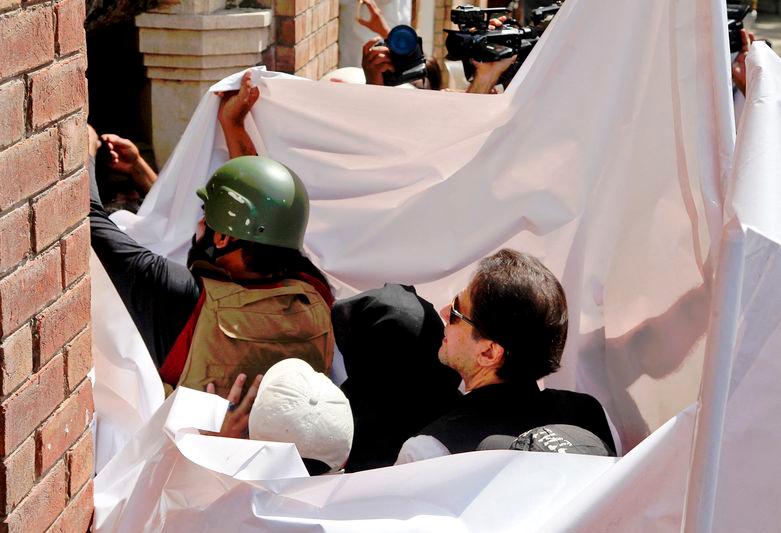 Pakistan’s former Prime Minister Imran Khan and his wife Bushra Bibi are covered with a white sheet as they arrive to appear at the High Court in Lahore - REUTERSpix