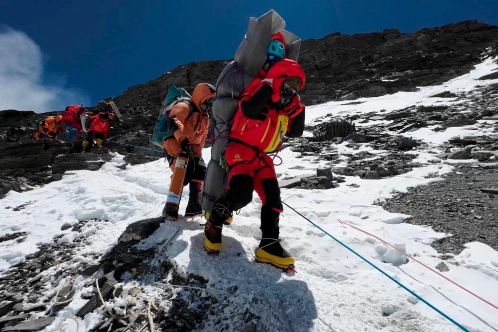 Ngima Tashi Sherpa walks as he carries a Malaysian climber while rescuing him from the death zone above camp four at Everest, Nepal, May 18, 2023 in this screengrab obtained from a handout video. - REUTERSPIX