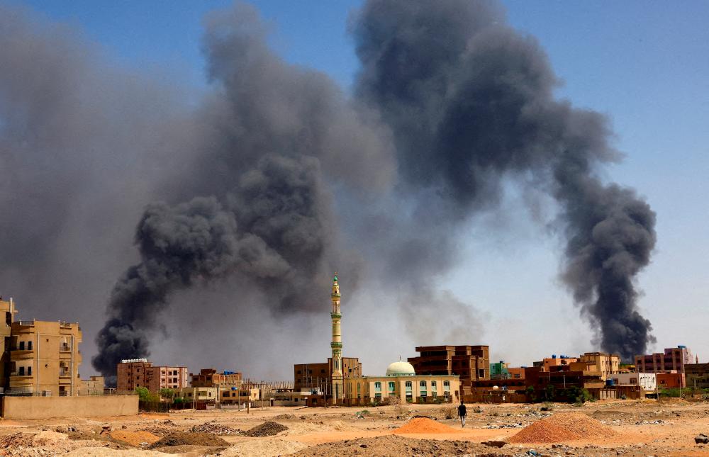 FILE PHOTO: A man walks while smoke rises above buildings after aerial bombardment, during clashes between the paramilitary Rapid Support Forces and the army in Khartoum North, Sudan, May 1, 2023. - REUTERSPIX