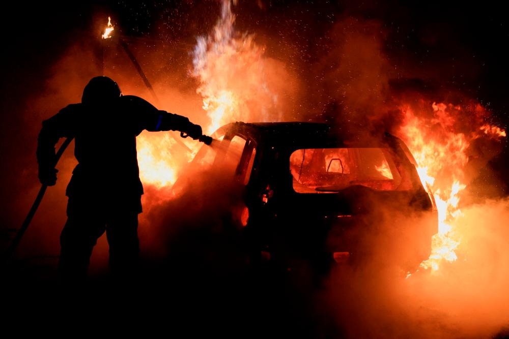 A French firefighter works to extinguish a burning car during the fifth day of protests following the death of Nahel, a 17-year-old teenager killed by a French police officer in Nanterre during a traffic stop, in Tourcoing, France, July 2, 2023/REUTERSPix