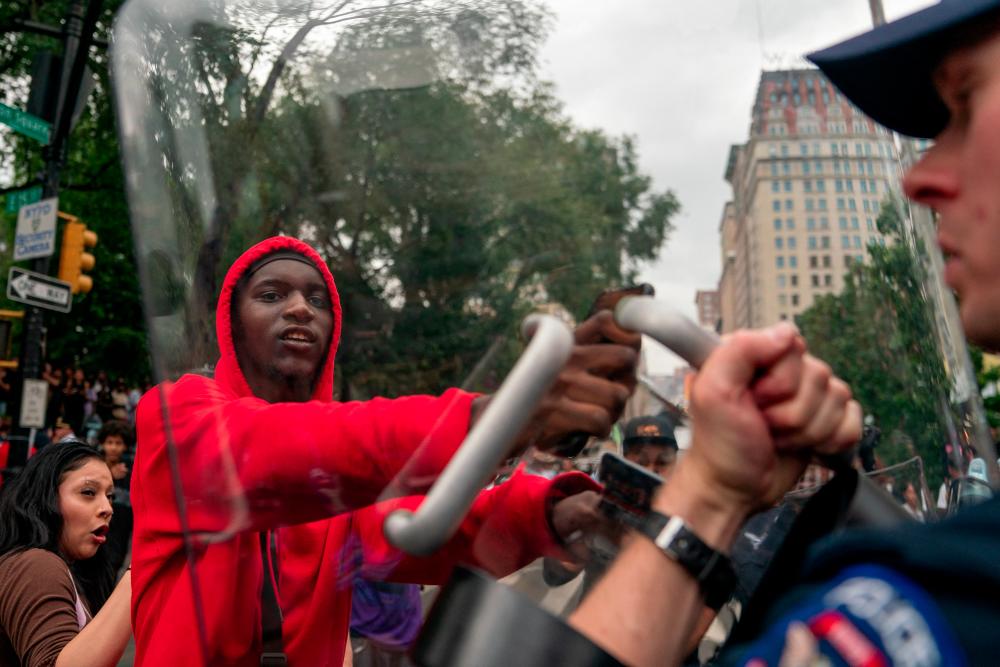 A police officer using a shield scuffles with a person after popular live streamer Kai Cenat announced a giveaway event that grew chaotic, prompting police officers to respond and disperse the crowd at Union Square and the surrounding streets, in New York City, U.S. August 4, 2023. - REUTERSPIX