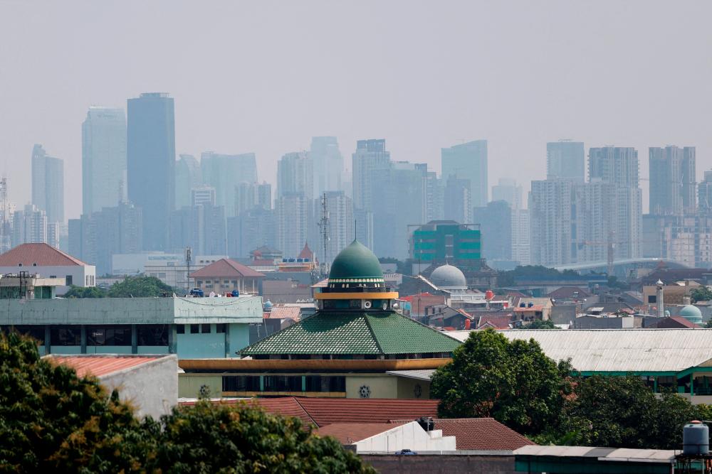 Mosques are seen in a residential area, as smog covers high-rise buildings in the background, in Jakarta, Indonesia August 9, 2023. REUTERSPIX