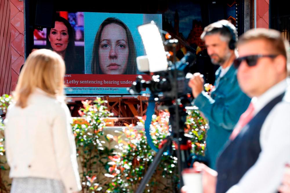 Filepix: Members of the media work near a large screen showing a picture of convicted hospital nurse Lucy Letby, ahead of her sentencing, outside the Manchester Crown Court, in Manchester, Britain, August 21, 2023/REUTERSPix