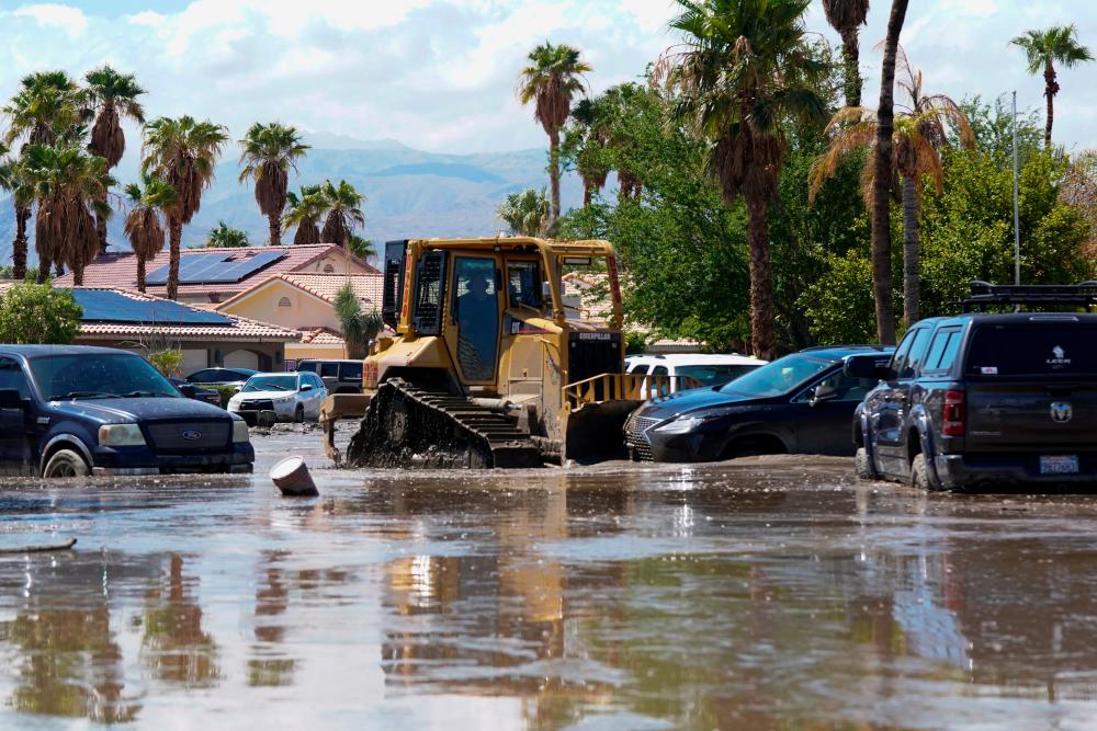 A bulldozer pushes cars out of the way to clear a partially flooded road following Tropical Storm Hilary in Cathedral City, California, U.S., August 21, 2023. REUTERSPIX